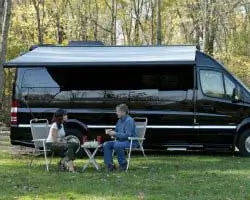 Campervan in a field with couple eating at table